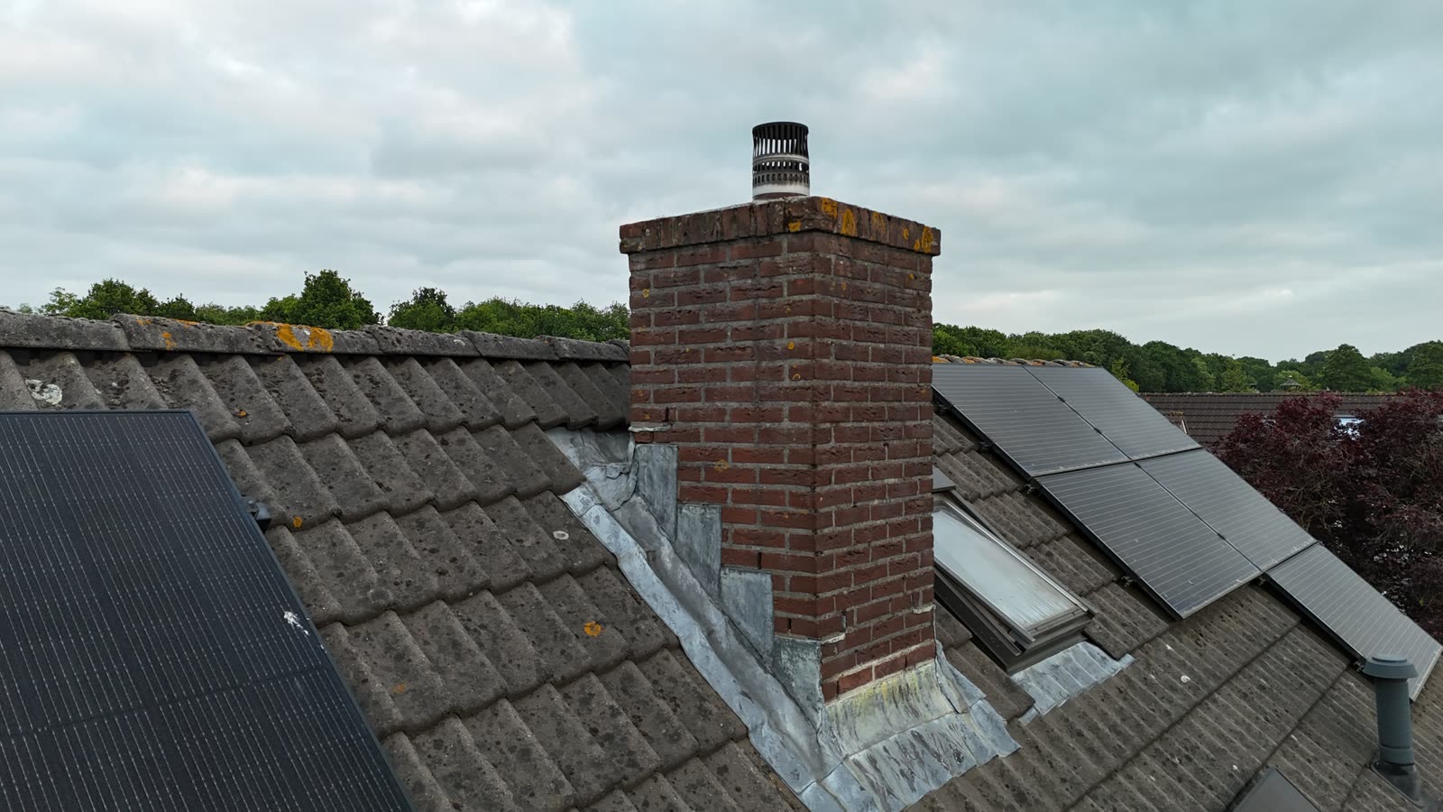 Drone-inspectie van een gemetselde schoorsteen met loodslabben, naast zonnepanelen